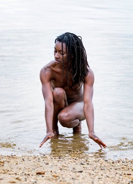 Naked black model posing on the river